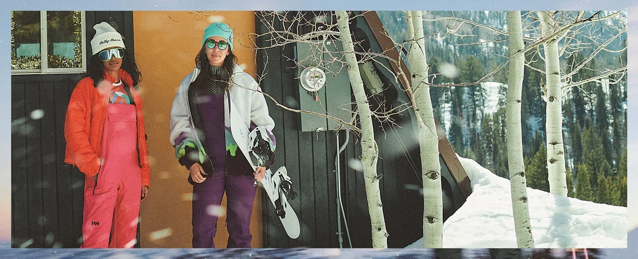 Two snowboarders next to a cabin.