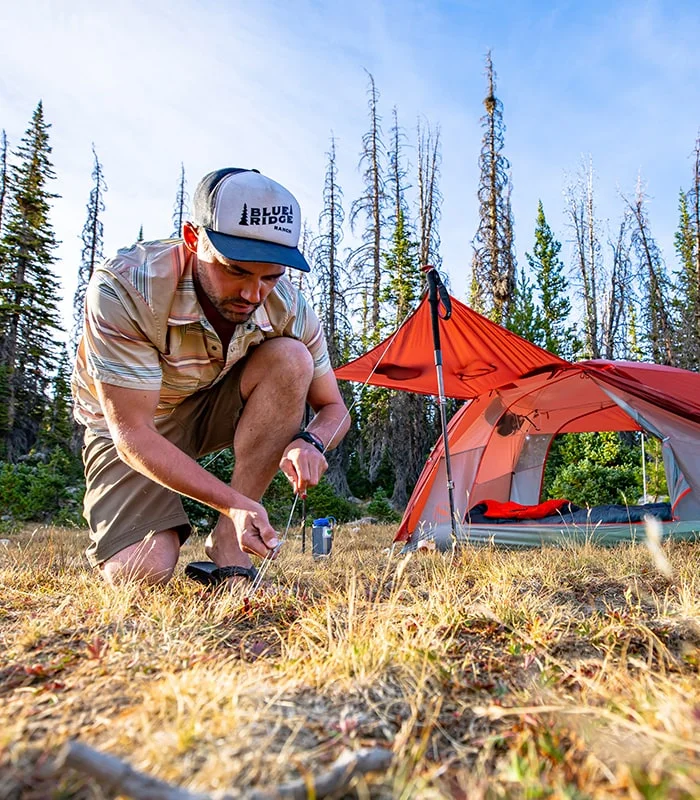 Man adjusting a tent stake line.