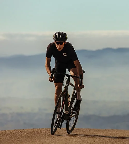 Cyclist on road with mountains in the distance.