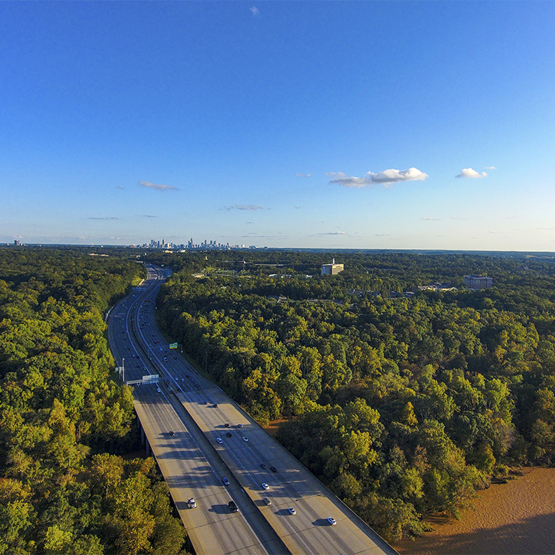 A aerial shot of vast miles of lush green trees, the freeway, the Chattahoochee river and blue sky at sunset at the Chattahoochee River National Recreation Area in Sandy Springs Georgia