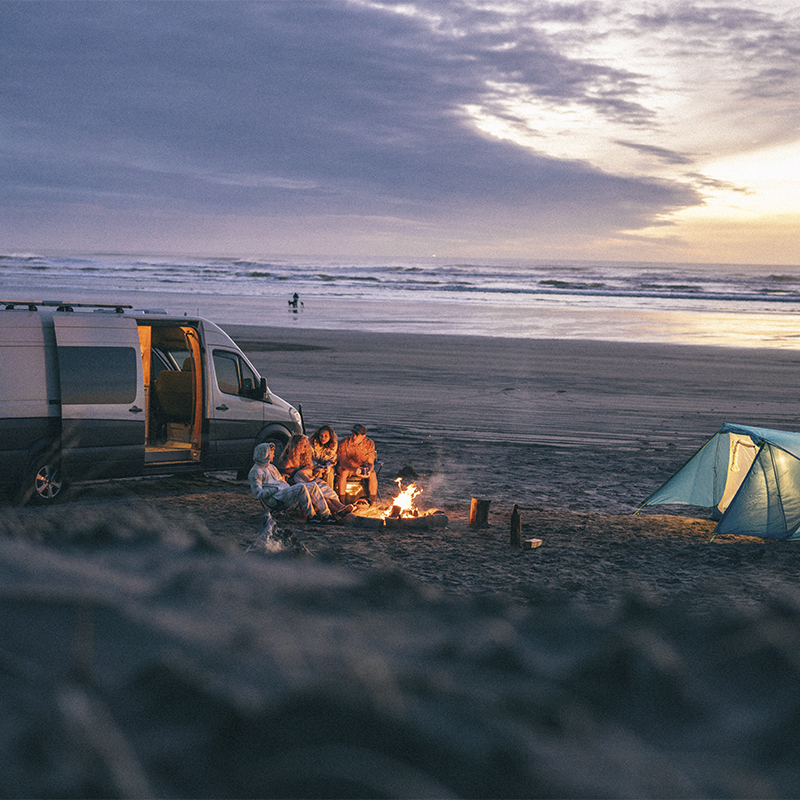 People camping on a beach with their van