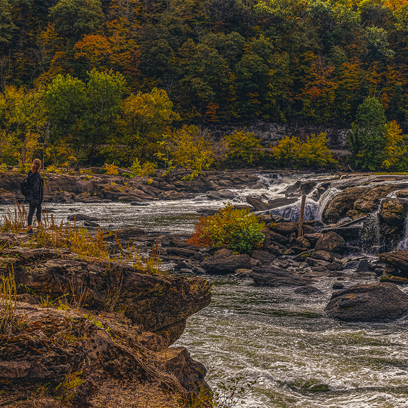 Female Hiker at Sandstone Falls With Fall Color, New River Gorge National Park, West Virginia.