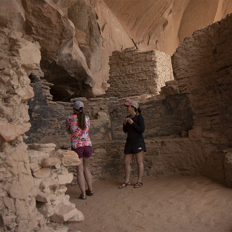 Two women from Public Lands look at the ruins of River House
