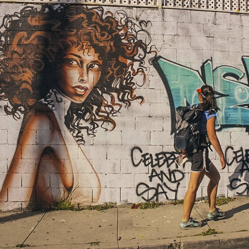 Liz Thomas walks around the city in front of a mural