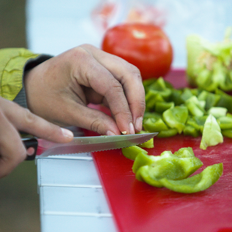 hand cutting peppers at a campsite