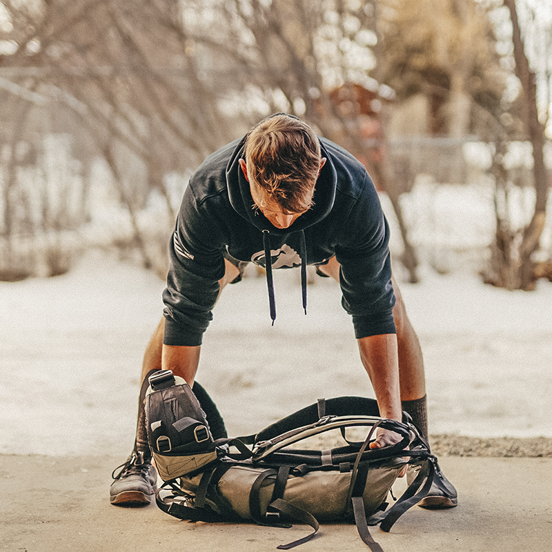A man uses a backpack to do a Heavy Pack Bent-over Row