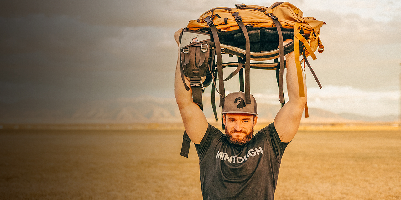 A man uses a backpack to do a Pack Sit-up Military Press
