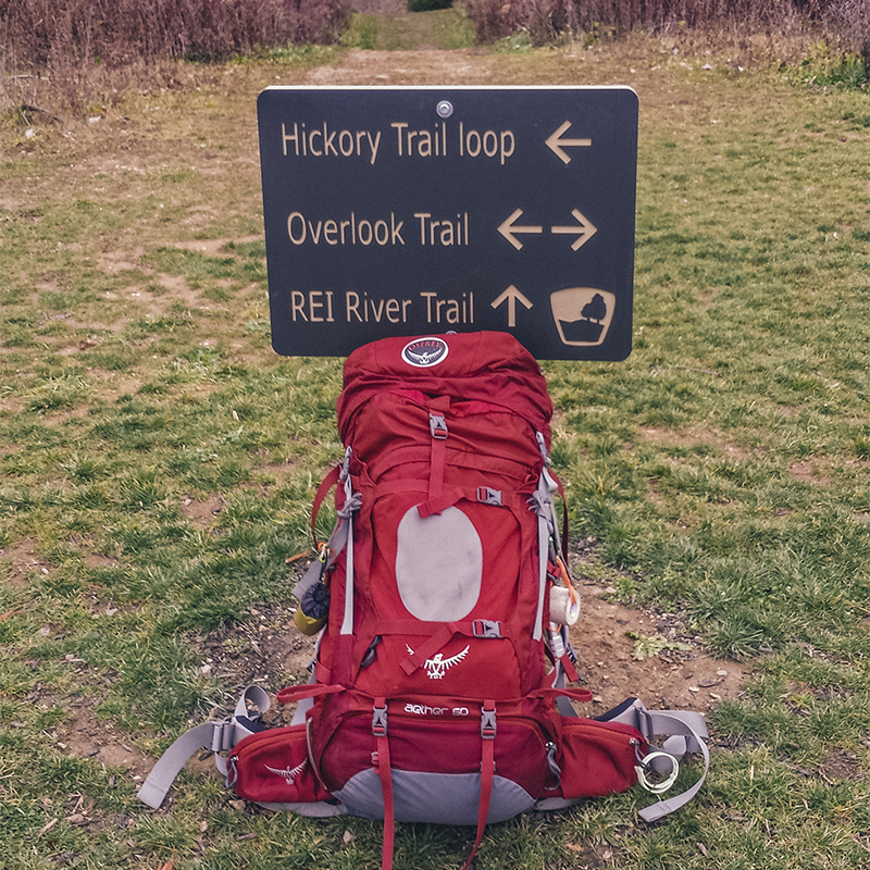 A backpacking bag sits next to a trail sign