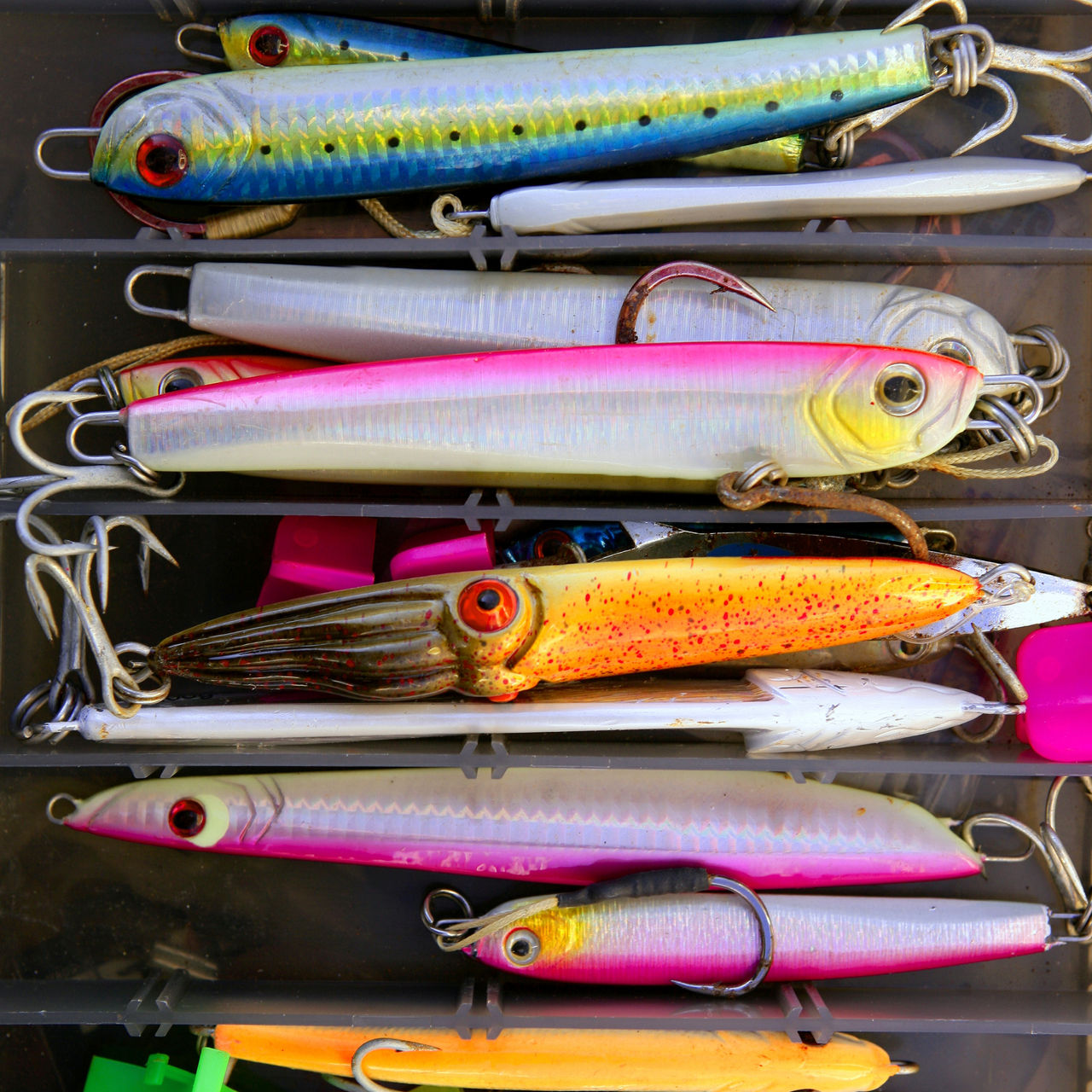 Colorful fishing saltwater fish lures in a box, rusted hooks