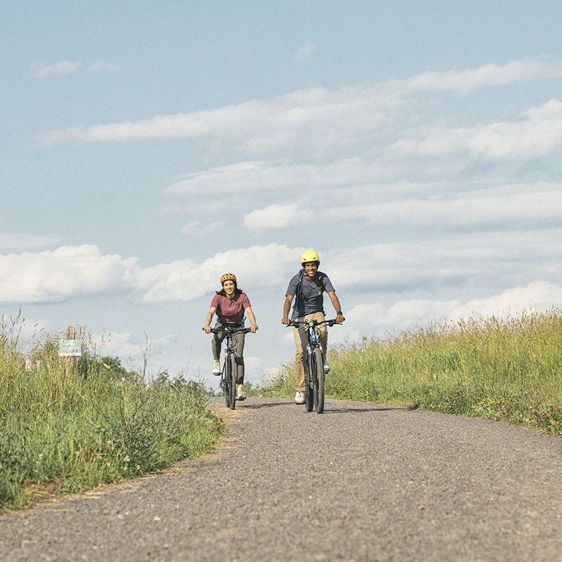 Two bikers biking on a gravel road