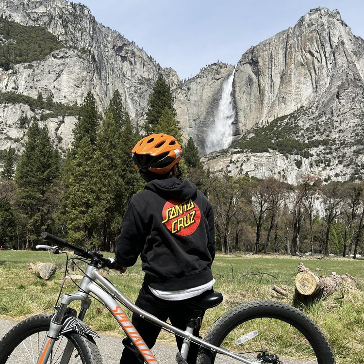 A biker looks up at a Yosemite waterfall