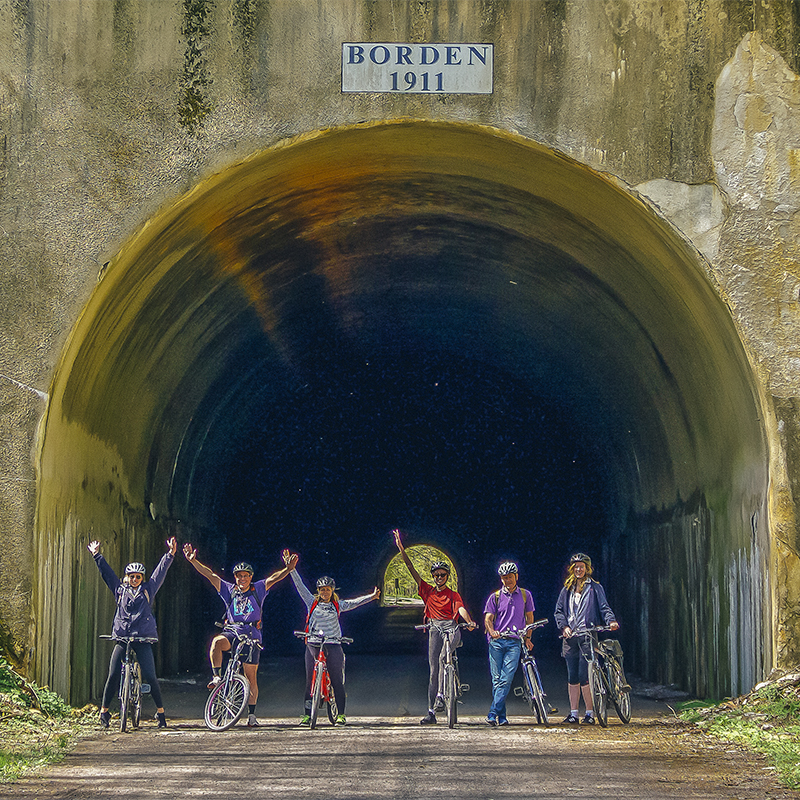 Bikers wave from the Borden tunnel on the Great Allegheny Passage trail