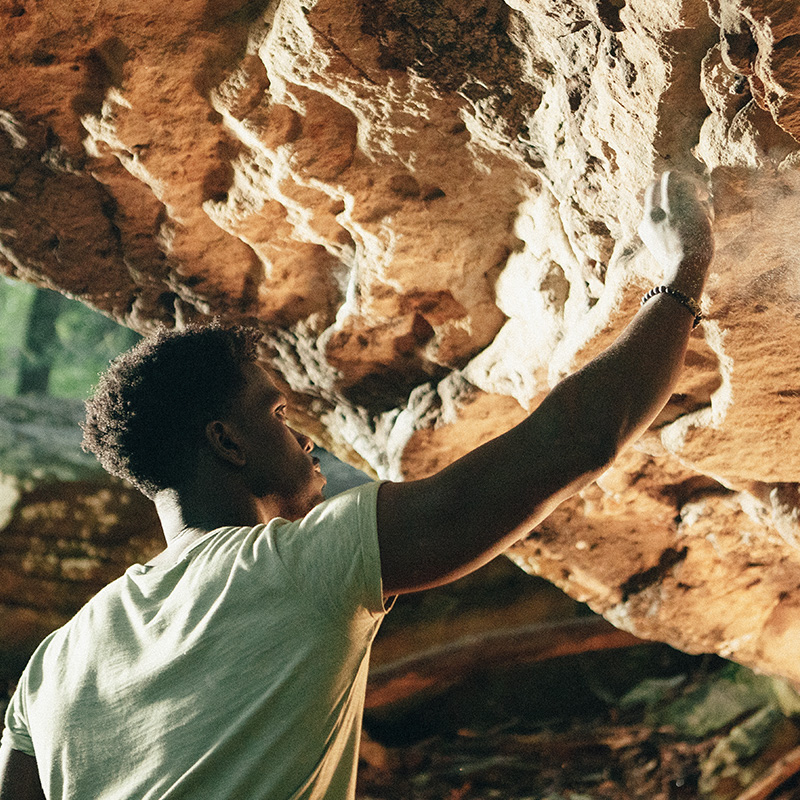 A man reaching up, chalking a boulder.