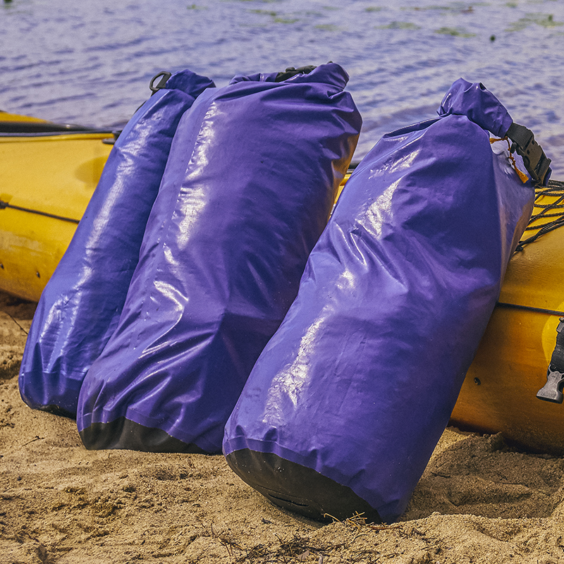 Dry bags sit next to a kayak