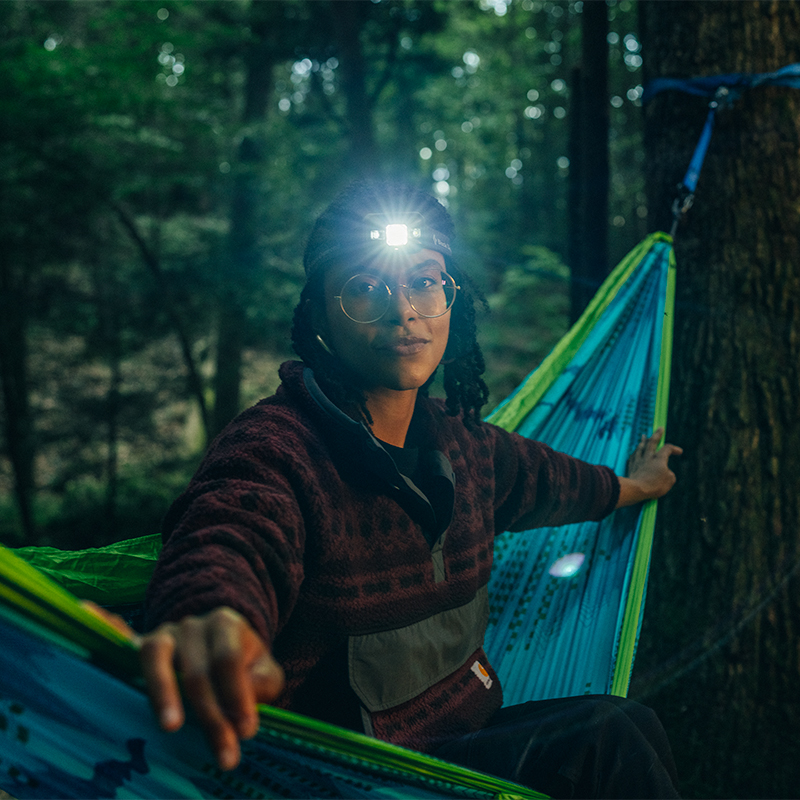 Camper with headlamp on a hammock