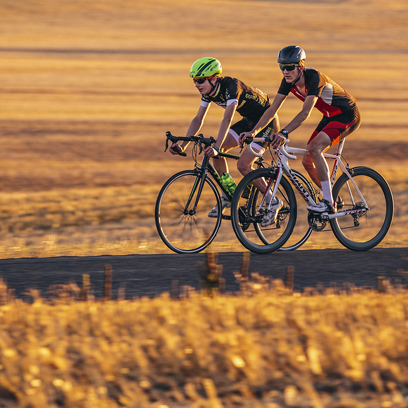 two cyclists training on bikes on a flat road