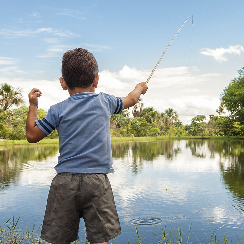Kid learning how to fish, holding a rod on a lake