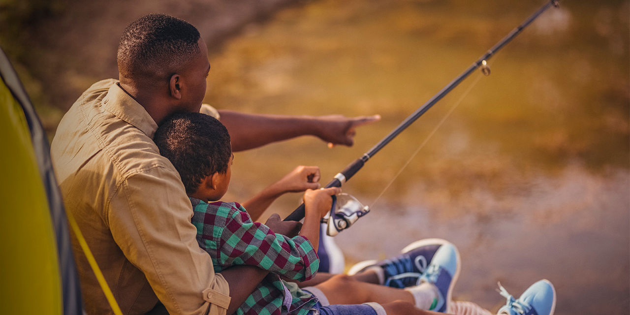 Father and son fishing together in park