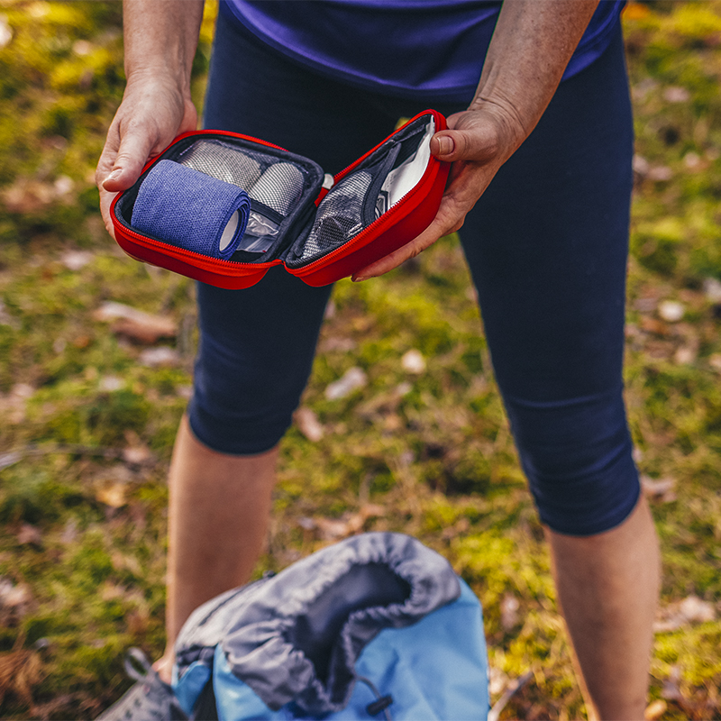 Woman opening first aid kit outdoors.