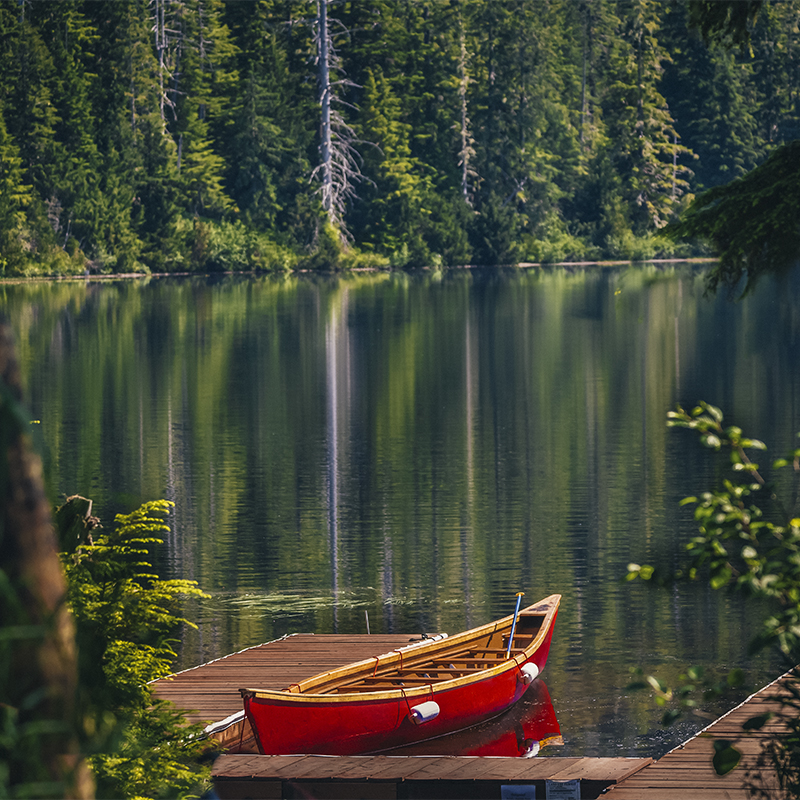 A red canoe docks at the mountain lake in Tongass National Forest of Alaska. 