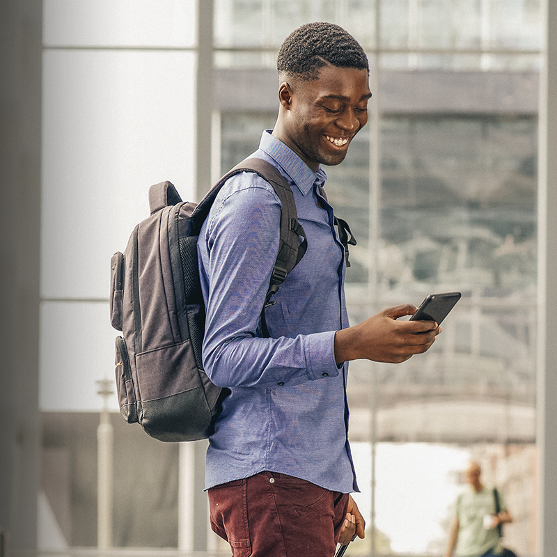 A young man traveling with backpack and cellphone at airport 