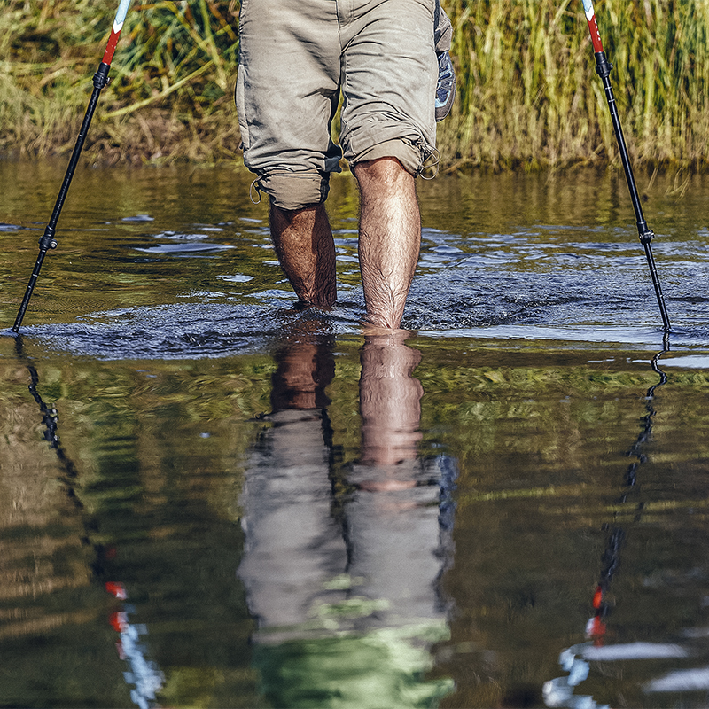 A person crosses a river with poles