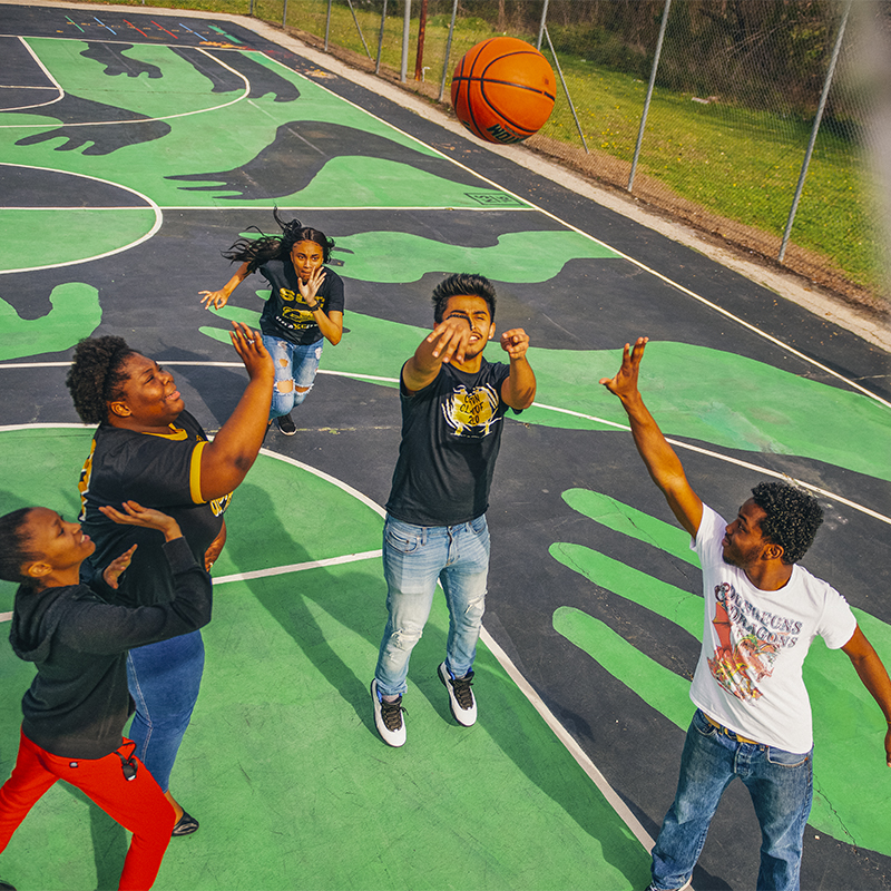 Kids play basketball on a painted court 