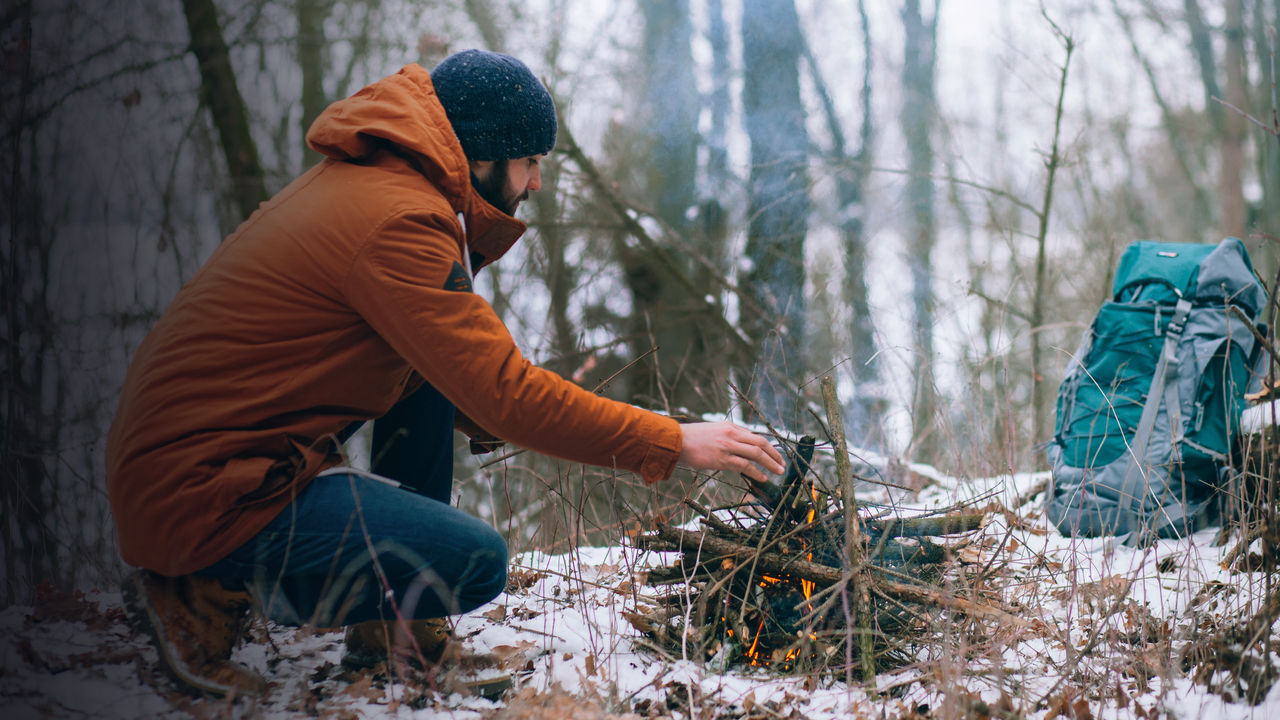 A man making camp fire in the winter woods