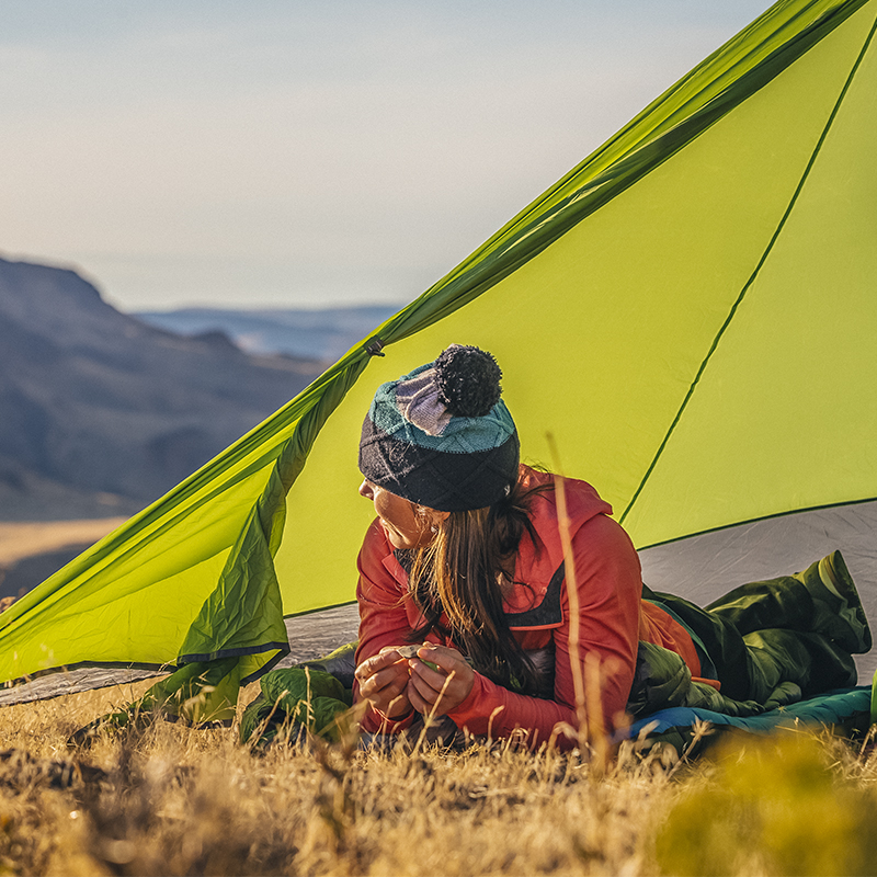 A woman looks out of her mountain tarp tent