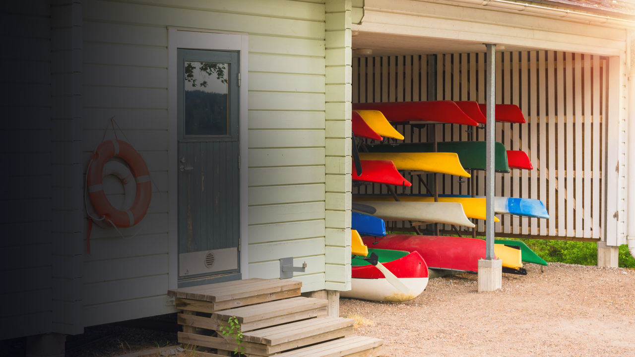Collection of vibrant colorful plastic recreational canoe and kayaks stored storage rack