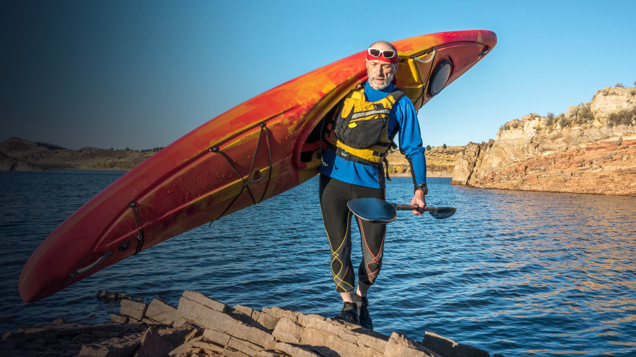 carrying river kayak on lake shore