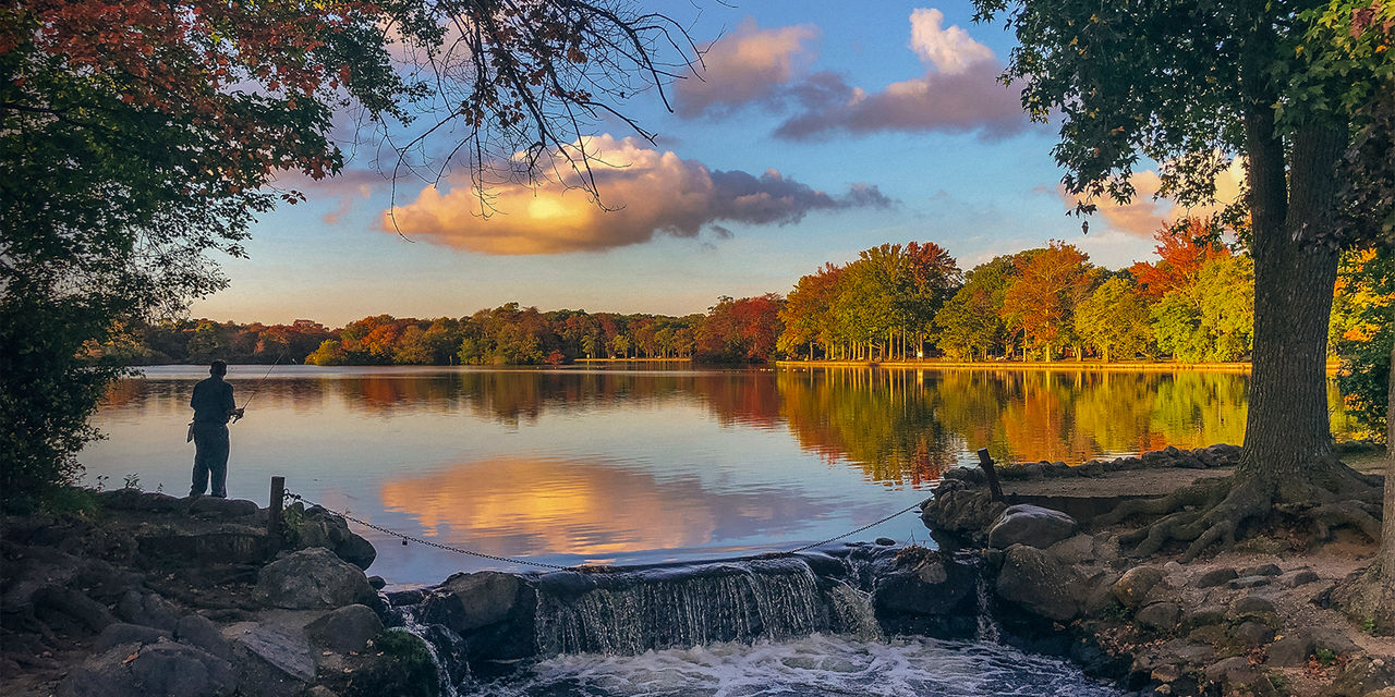 A man fishing next to a waterfall on Long Island, New York