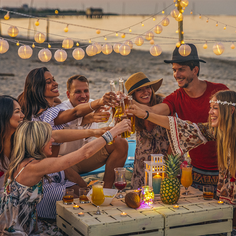 Group of friends under lights having a celebration at the beach