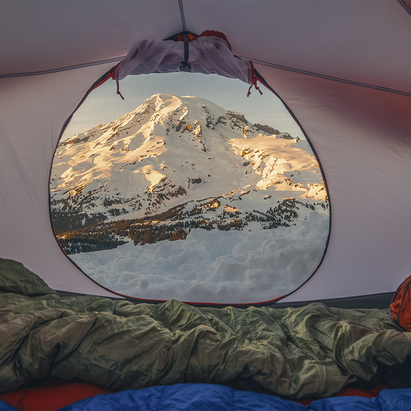 A snowy sunset on Mount Rainier as seen through a tent door.