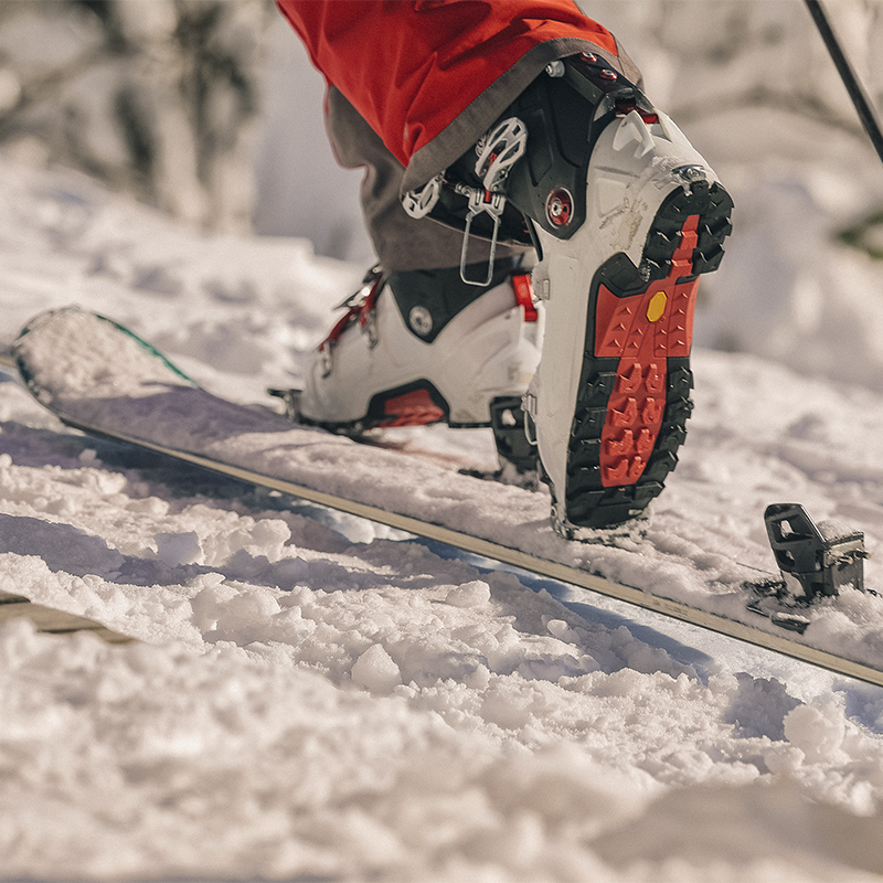 Close up of ski boots stepping onto snowy ski