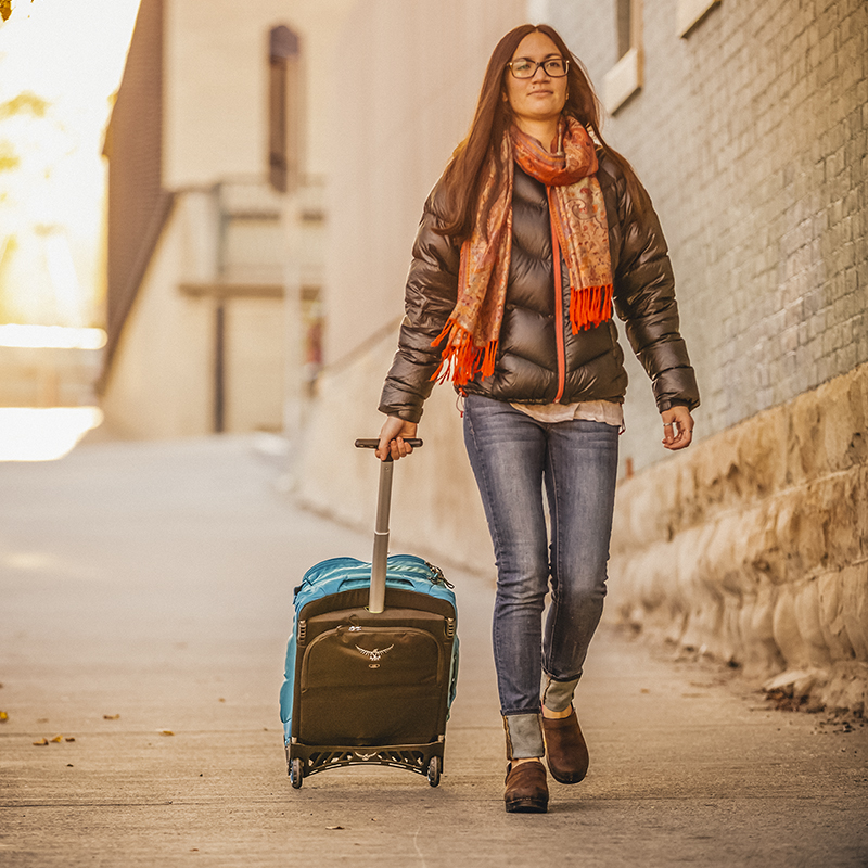 A woman walks with her carry on luggage through the streets of Durango