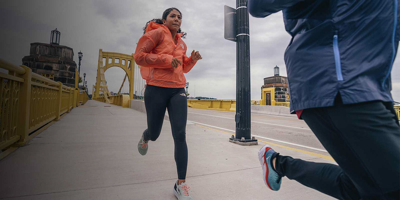 Male and female runners running on sidewalk