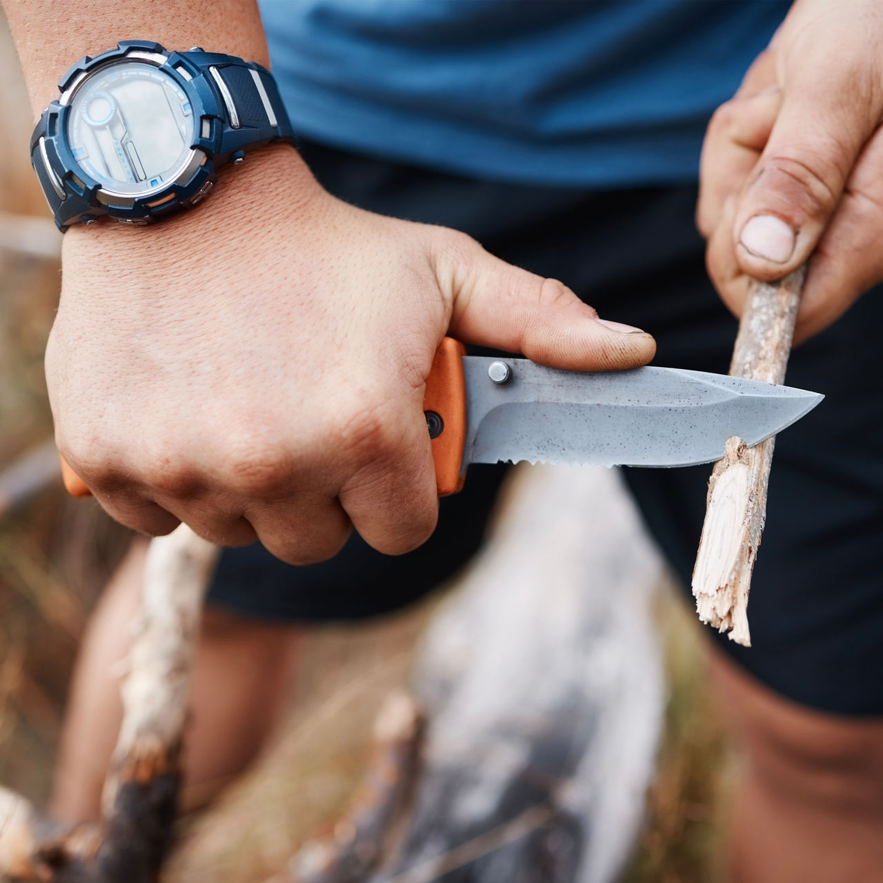 A close up of a camping knife cutting a stick 