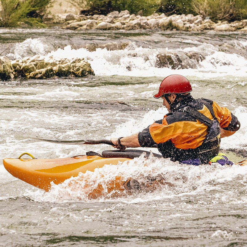 A kayaker in a dry suit navigates whitewater 