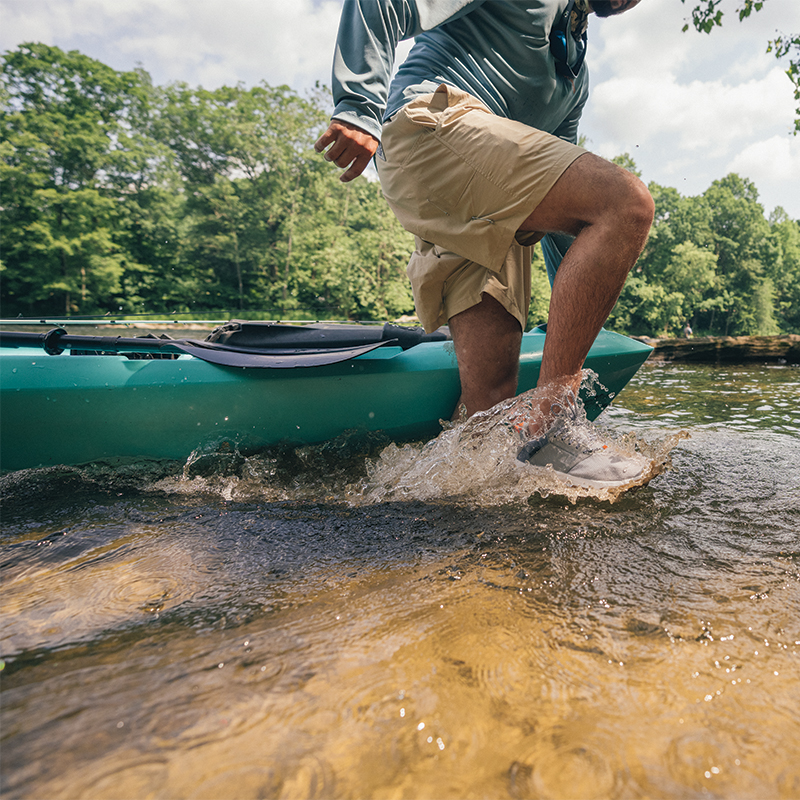 A man pulling his boat through shallow water.