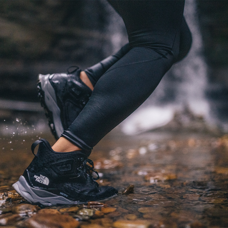 Close up on shoes of someone running through a creek