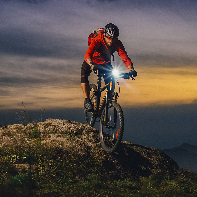 A man rides his mountain bike at dusk with a bike light