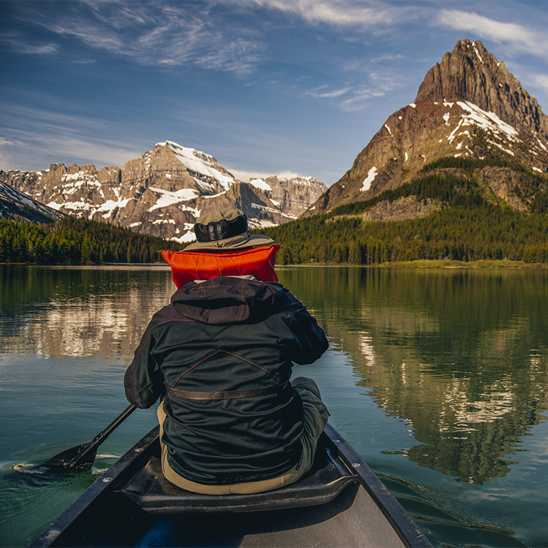 A person paddles on Swiftcurrent Lake during sunrise in Montana