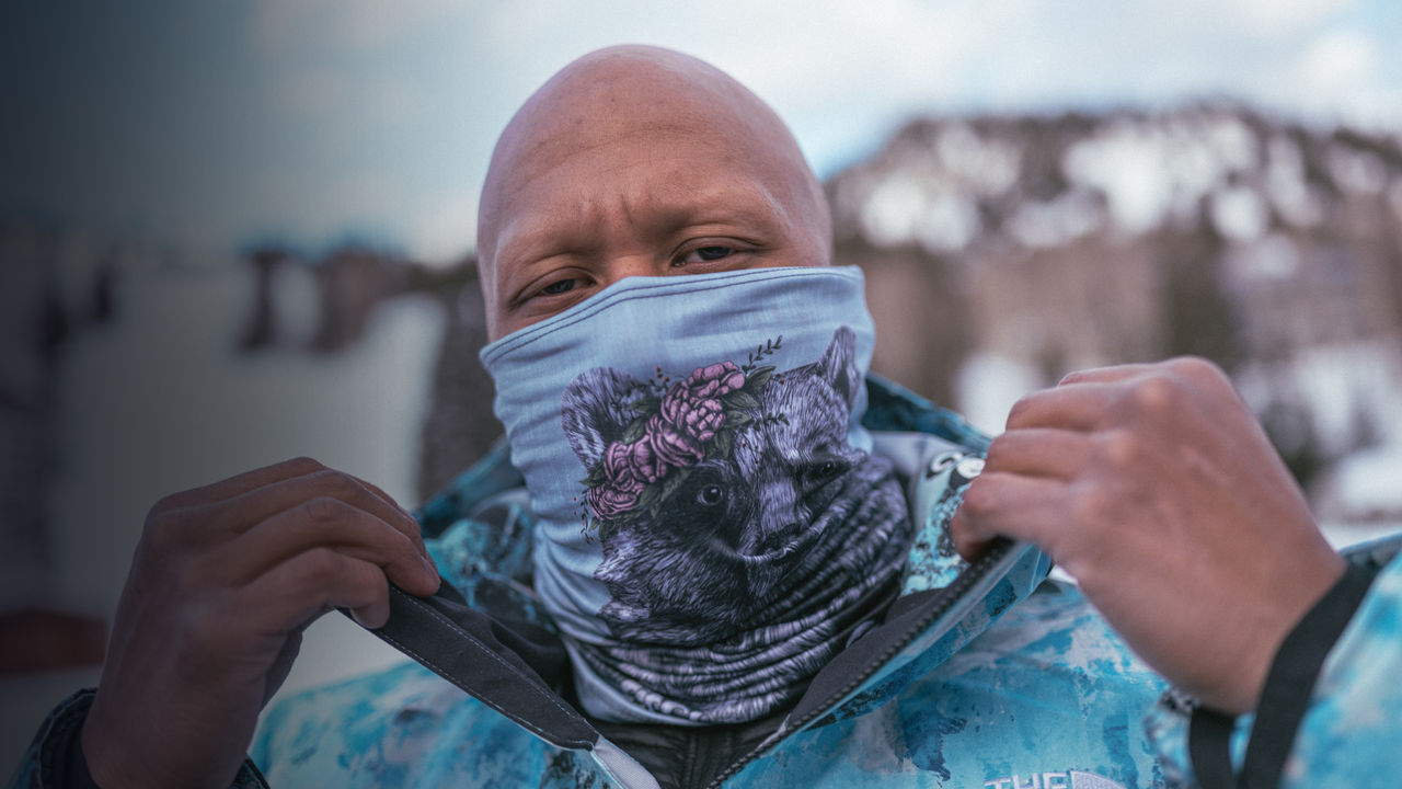 A snowboarder puts on a face mask