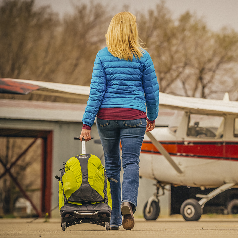 A woman takes her luggage to a plane in a small, local  airport 