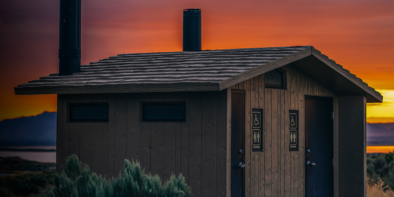 Sunrise on Great Salt Lake in Antelope Island State Park from Ladyfinger campground in Utah with restroom bathroom cabin building and sign