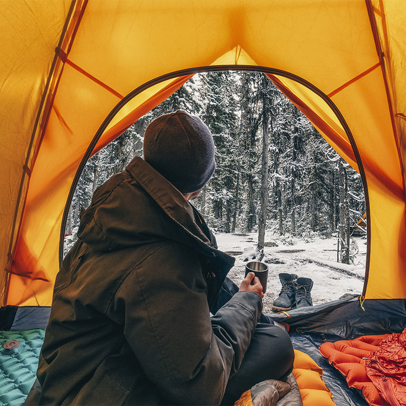 A person looks outside their tent in the winter