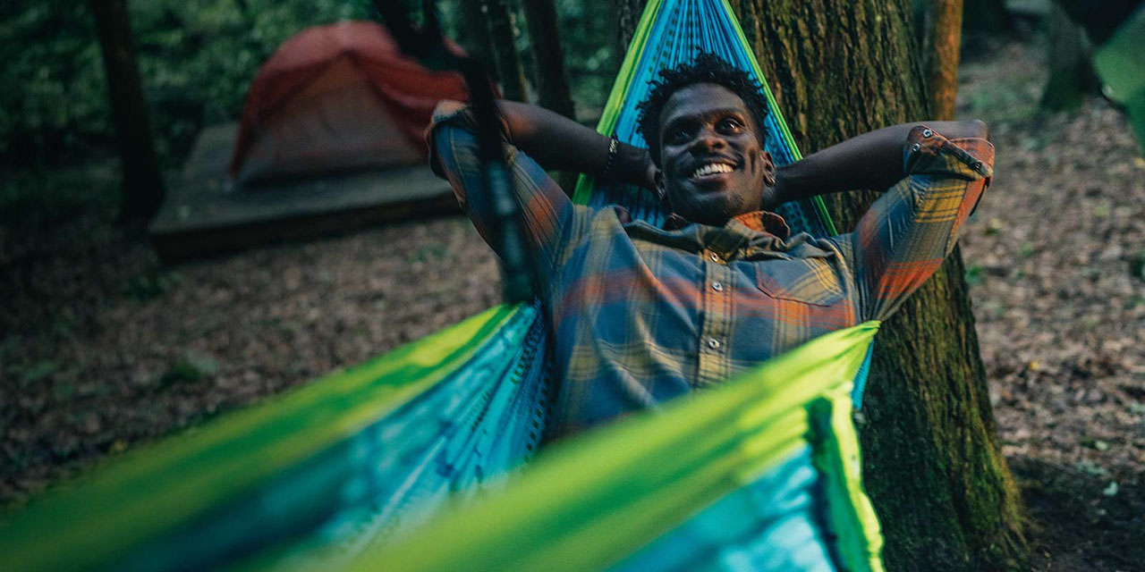 Camper laying in a hammock in the woods