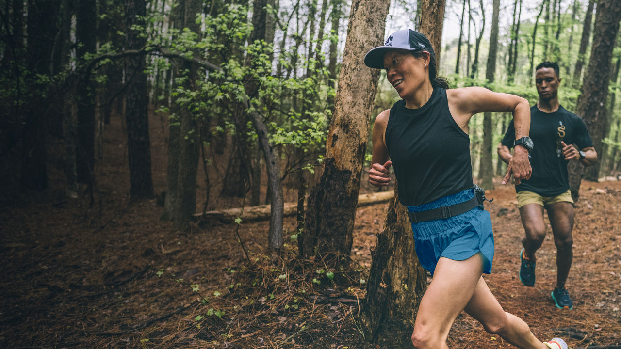 Two runners run in the forest