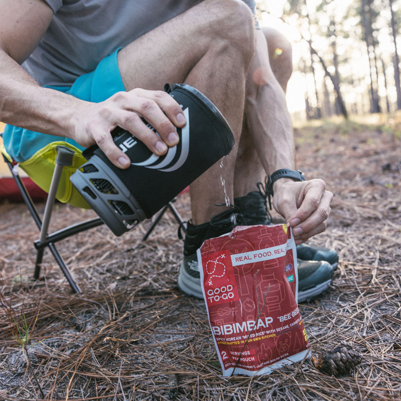 A person pours water from a Jetboil into a camping meal